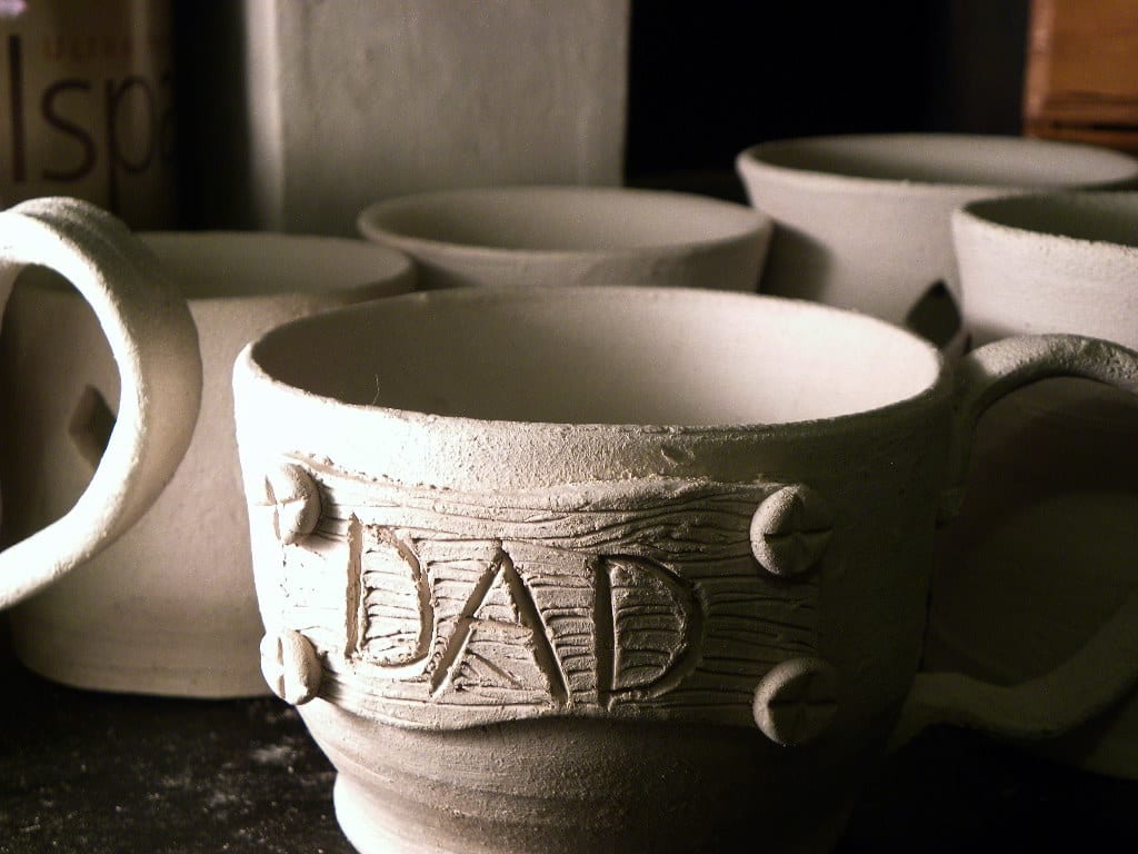 Unfired greenware pots drying on a shelf, waiting for a bisque firing