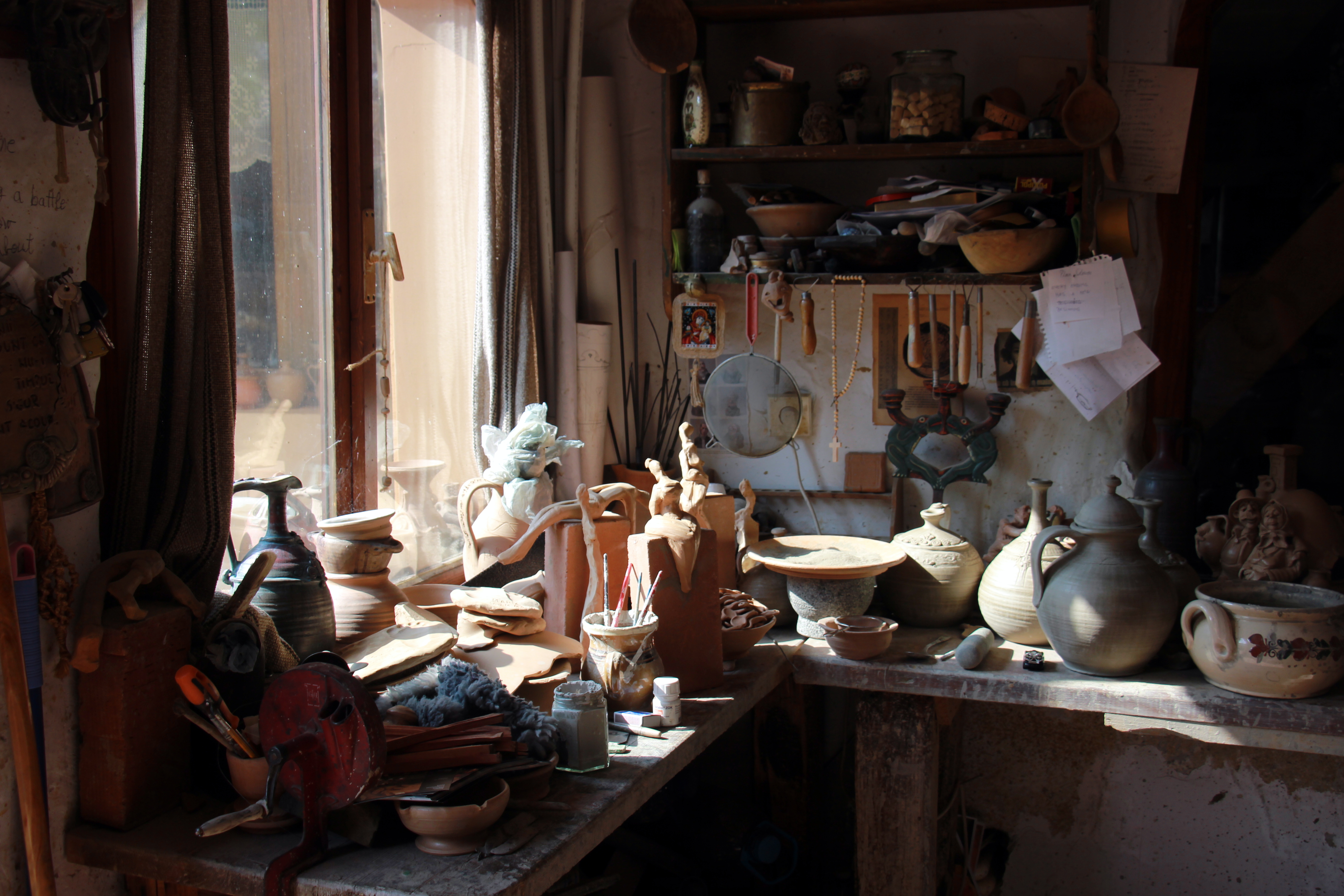 Ceramics workshop interior showing home studio layout with kiln and ware boards for pottery production