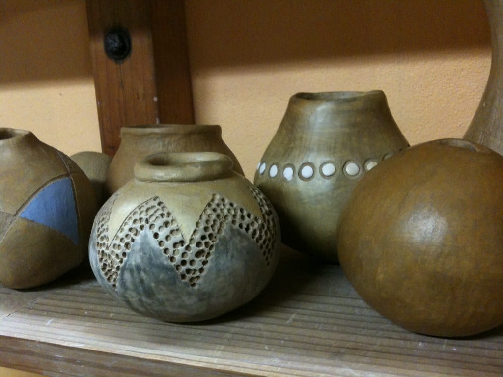 Small hand-built pots arranged on a shelf, ready to be loaded for a bisque firing