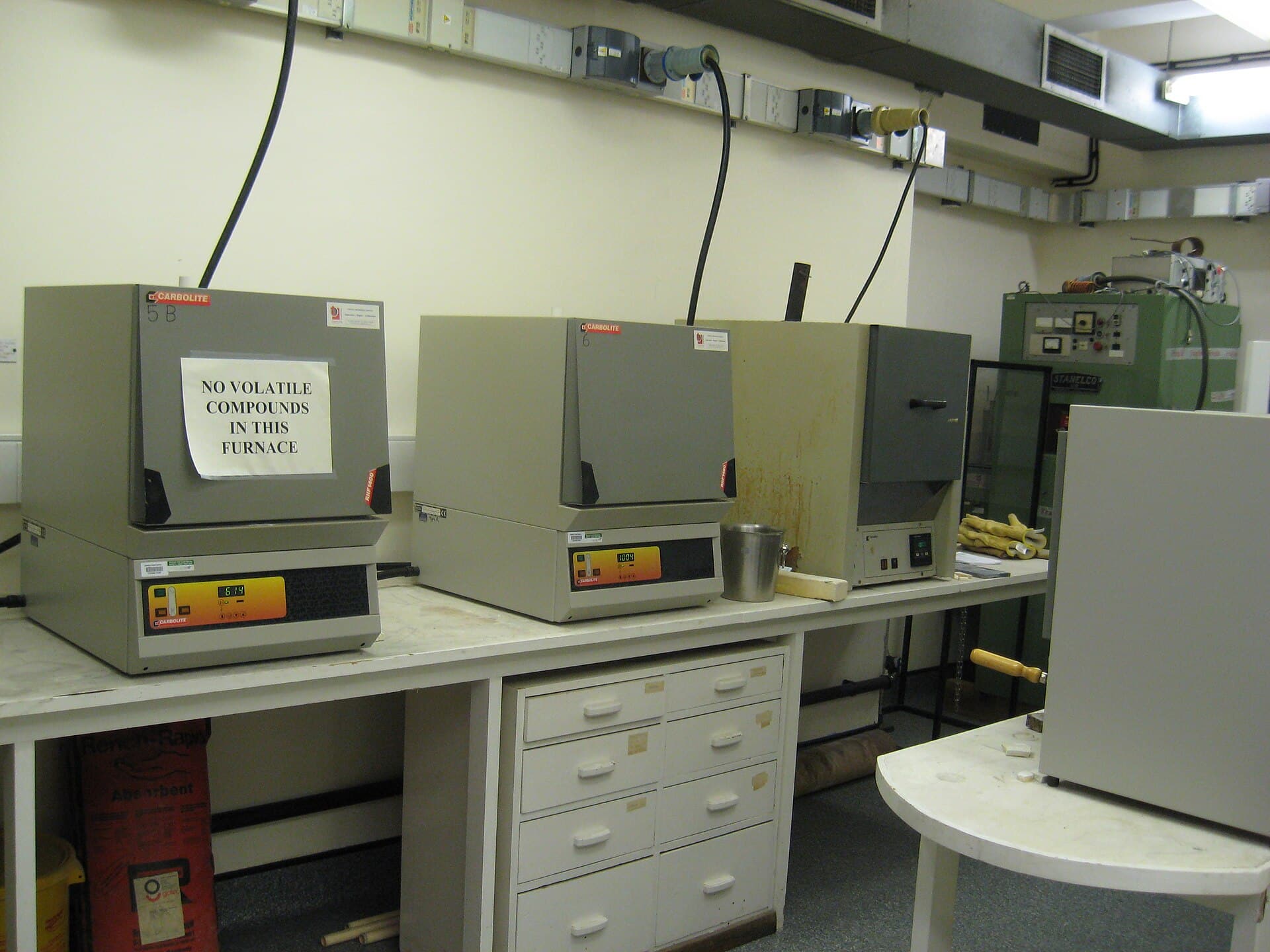 Two front-loading muffle furnaces sitting on a laboratory bench with controllers on the front panel