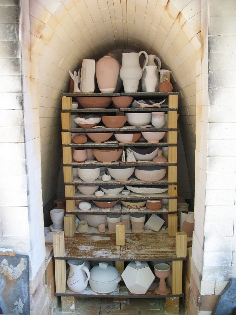 A kiln partially loaded with pottery on stacked shelves and posts