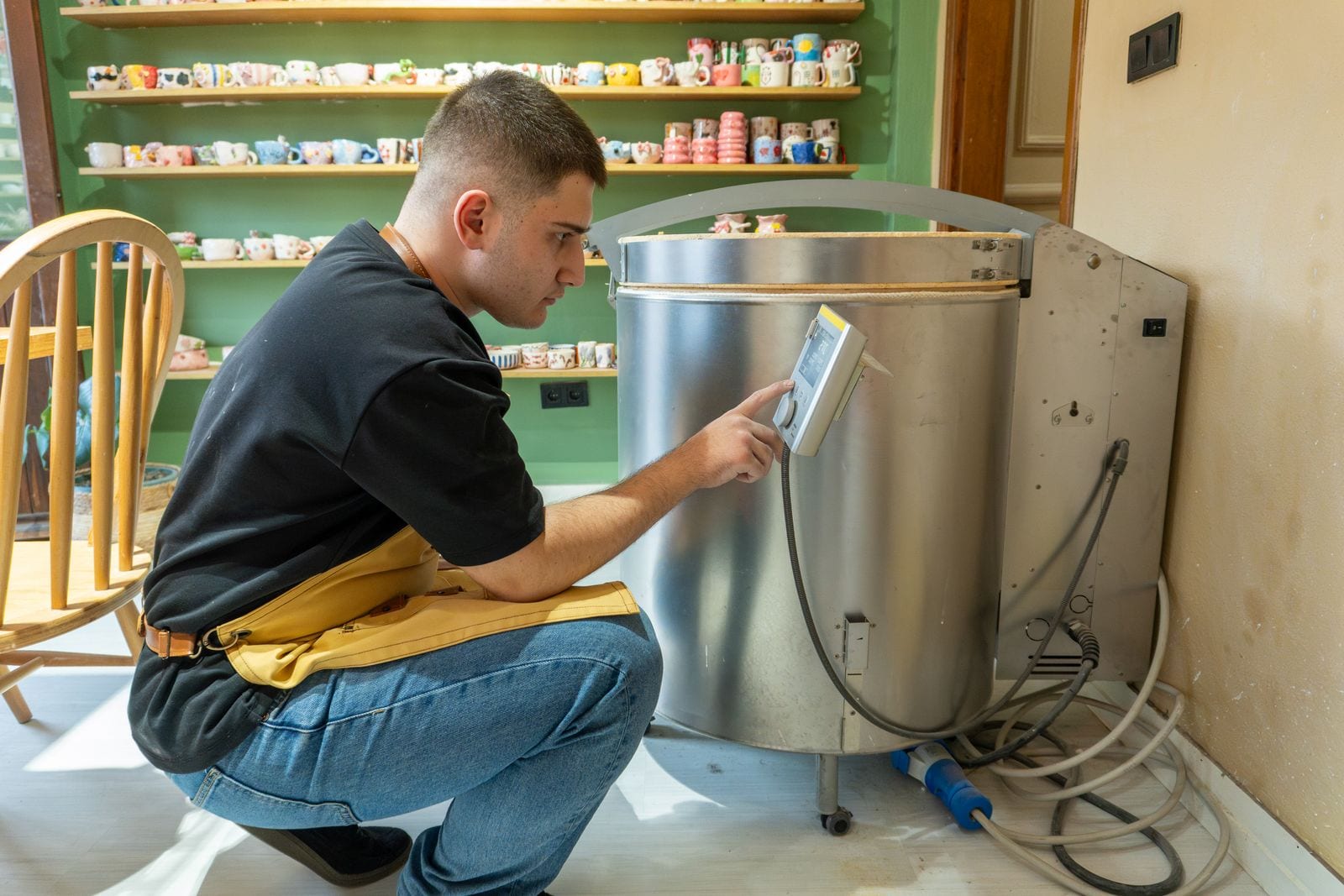 Potter operating the digital control box on the side of an electric kiln
