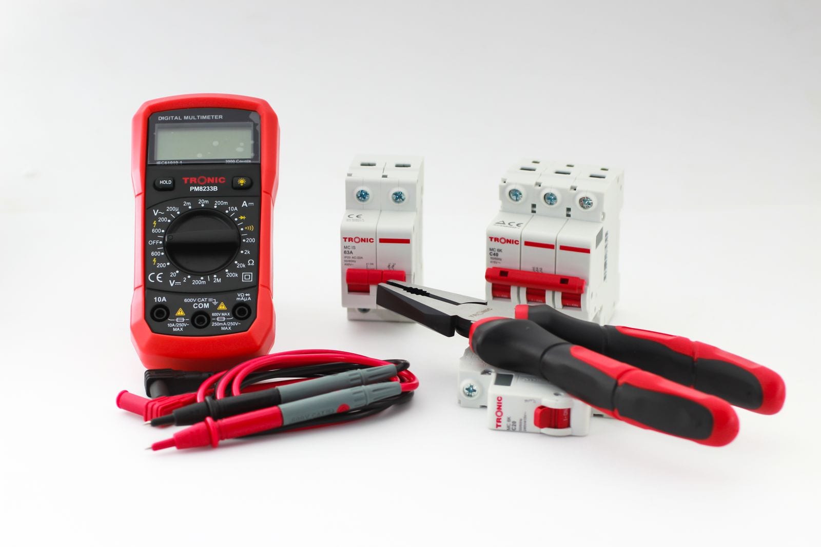 Digital multimeter with test leads beside miniature circuit breakers and pliers