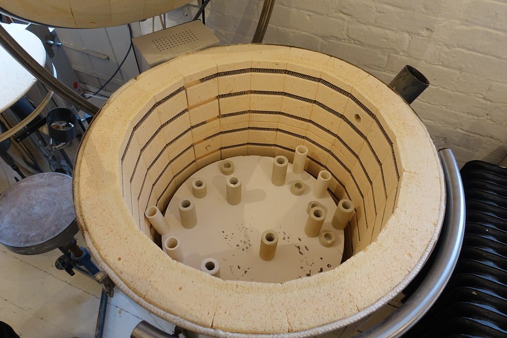 Top-down view into an open electric kiln showing heating element coils in their grooves