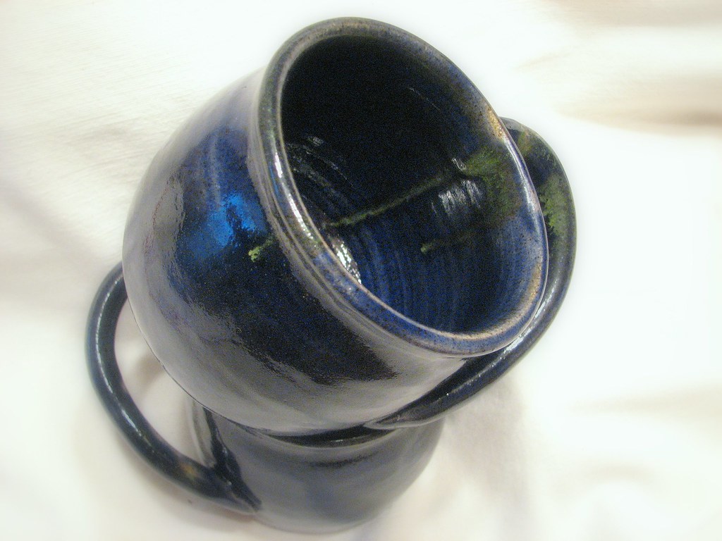 Row of finished handmade ceramic mugs with colorful glazes after firing