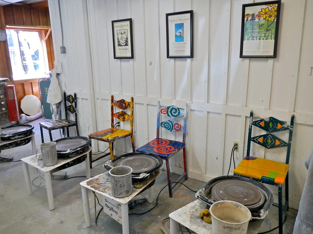 A ceramics studio corner with pottery wheels and an electric kiln by the window