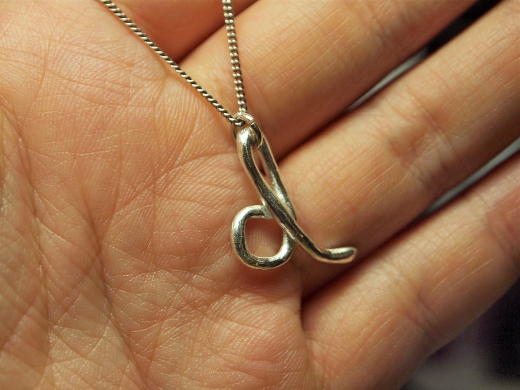 A finished silver pendant with a looped design resting in an open hand