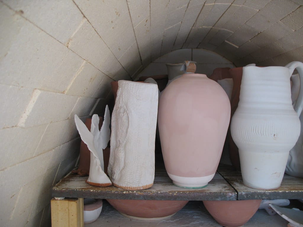 Greenware pieces loaded on shelves inside a studio electric kiln before firing