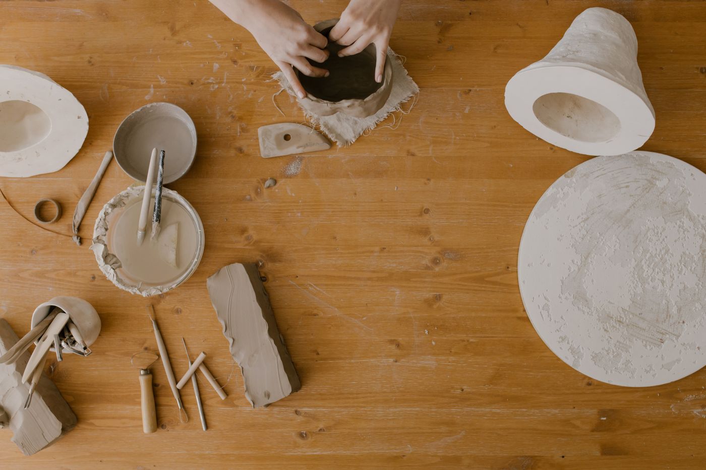 Overhead view of bats, ribs and clay tools laid out on a wooden work bench
