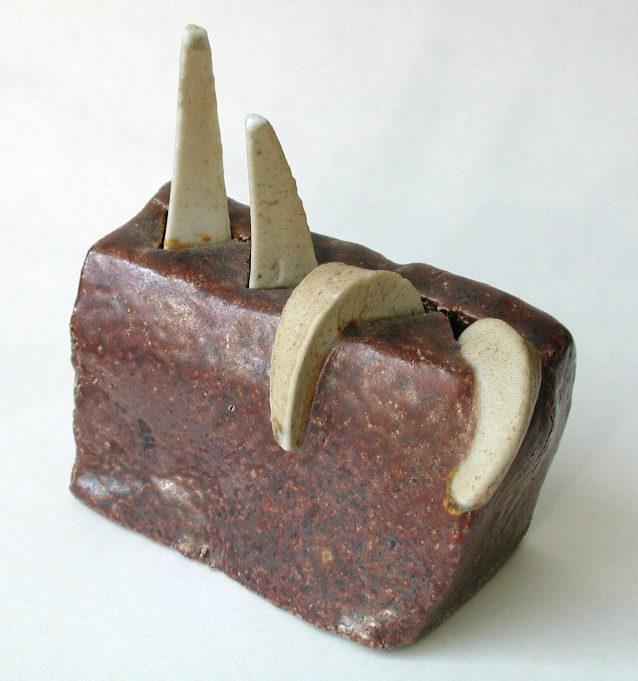 Three pyrometric cones mounted on a fired clay plaque, one upright and two bent over