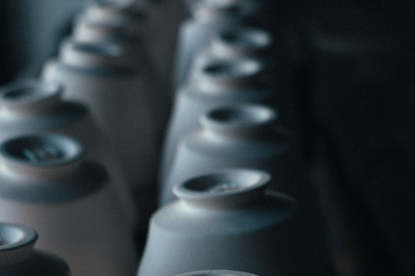 Rows of finished ceramic cups stacked upside down on a workshop shelf
