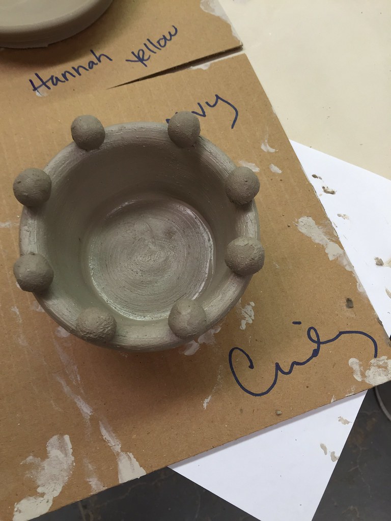 Community ceramics studio during an evening pottery class with multiple students at wheels