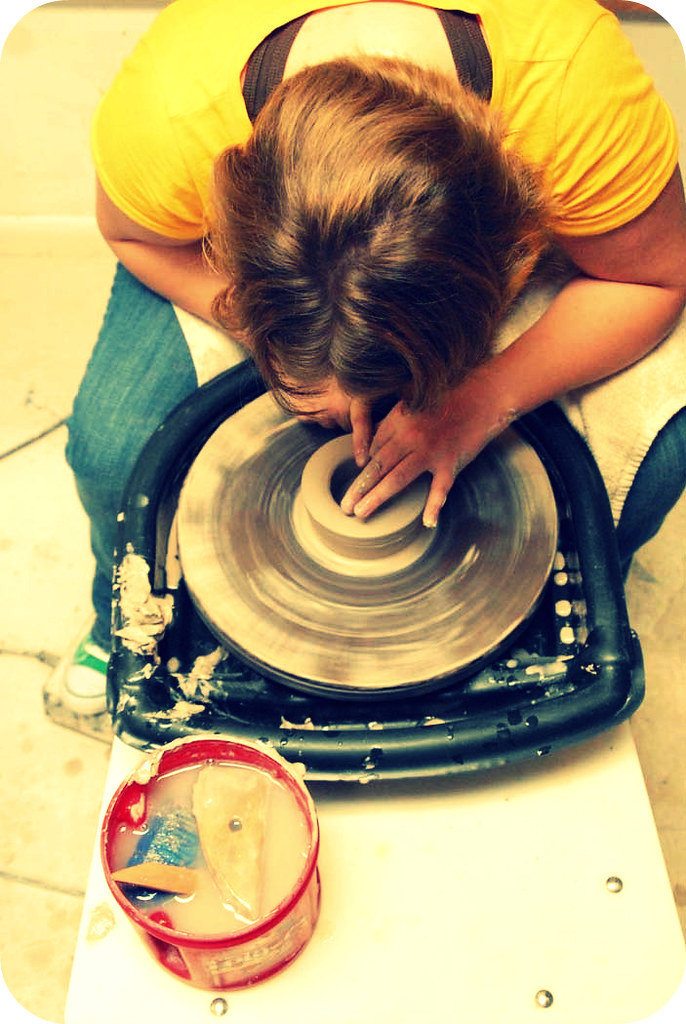 Potter opening and centering a ball of clay on a wheel head