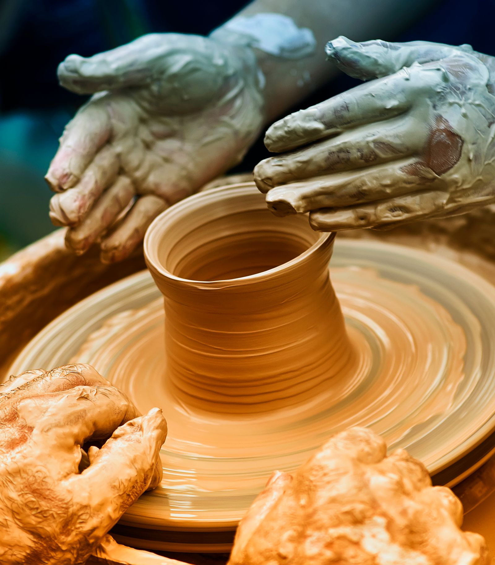 Potter's hands centering a large ball of clay on a pottery wheel