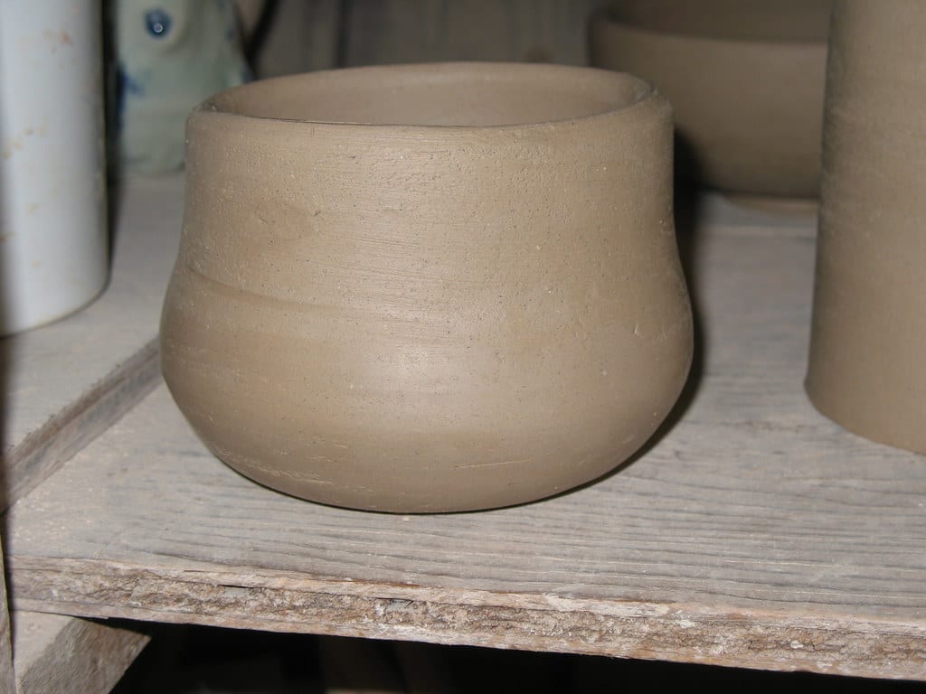 A potter's hands on a freshly centered mound of clay on the wheel